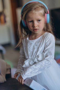 Beş yaşındaki neşeli bir kız doğum günü hediyesi olarak bir çift kulaklık aldığında heyecanla ışıldıyor. Yüksek kalite fotoğraf