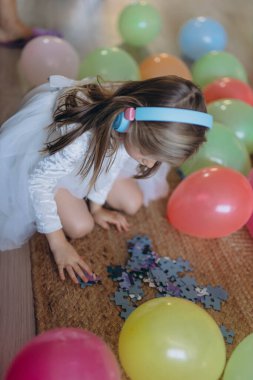 5 yaşındaki kızımın doğum günüydü. Kulaklıkla müzik dinler ve bir yapboz toplar. Bir sürü balon var. Yüksek kalite fotoğraf