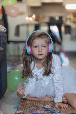 5 yaşındaki kızımın doğum günüydü. Kulaklıkla müzik dinler ve bir yapboz toplar. Bir sürü balon var. Yüksek kalite fotoğraf