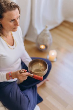Şarkı söyleyen Tibet kâsesinde oynayan genç bir kadın. Rahatlama ve meditasyon. Şarkı söyleyen bir kâseye yakın çekim. Yüksek kalite fotoğraf