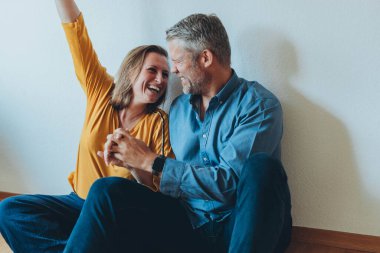 Mutlu bir çift yerde otururken evde eğleniyor. Yüksek kalite fotoğraf