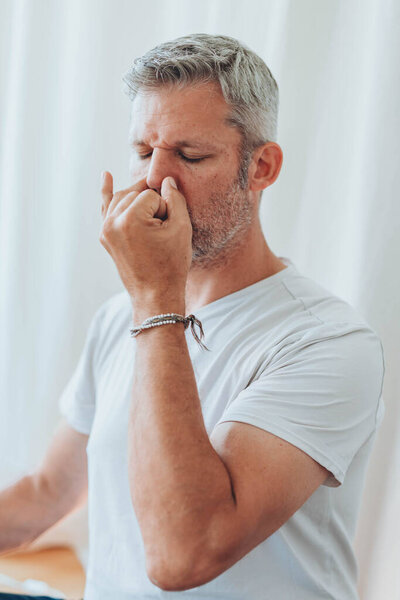 A man sitting in lotus position, practicing alternate nostril breathing exercises during a meditation session. High quality photo