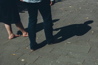 Bir adam ve bir kadın çıplak ayakla yürüyorlar, gölgeleri yere düşmüş. Yüksek kalite fotoğraf