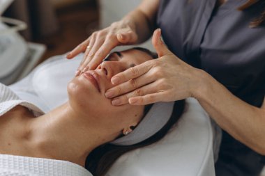 Güzel bir kadın güzellik salonunda cilt ve vücut bakımına düşkün bir yüz masajından hoşlanıyor. Yüksek kalite fotoğraf