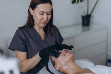 Kozmetik uzmanı genç bir kadın üzerinde yüz soyma işlemi yapıyor. Yüksek kalite fotoğraf