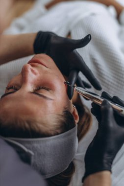 Kozmetik uzmanı genç bir kadına ultrasonik spatulayla yüz bakımı yapıyor. - Evet. Yüksek kalite fotoğraf