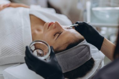 Kozmetik uzmanı genç bir kadın üzerinde yüz soyma işlemi yapıyor. Yüksek kalite fotoğraf