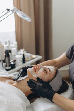 Kozmetik uzmanının kapanışı salondaki kadın müşteriler için yüz maskesi yapıyor. Dermatoloji, güzellik konsepti. Yüksek kalite fotoğraf