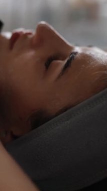 Kozmetik uzmanı, güzellik salonunda cilt bakımına odaklanmış genç bir kadının cildini temizliyor.