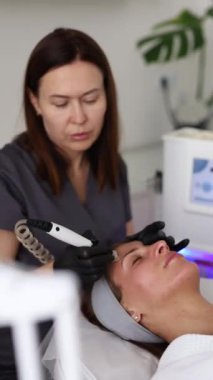 Tıp eldivenli profesyonel dermatolog güzellik salonunda bir kadına mikro cilt bakımı yapıyor.