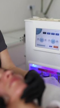 Tıp eldivenli profesyonel dermatolog güzellik salonunda bir kadına mikro cilt bakımı yapıyor.