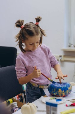 Çocuklar ve yetişkinler Cadılar Bayramı için balkabağı boyuyor, eğlenceli ve yaratıcı aktivitelerin tadını çıkarıyorlar. Yüksek kalite fotoğraf