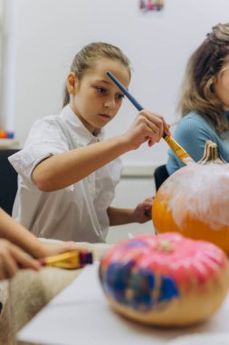 Children and adults painting pumpkins for Halloween, enjoying a fun and creative activity together. High quality photo clipart