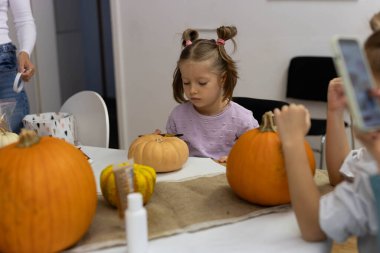 Children and adults painting pumpkins for Halloween, enjoying a fun and creative activity together. High quality photo clipart