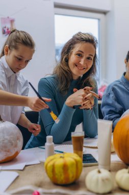 Children and adults painting pumpkins for Halloween, enjoying a fun and creative activity together. High quality photo clipart