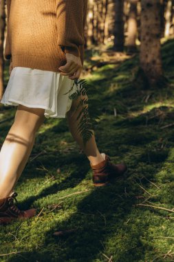 Genç bir kadın elinde eğrelti otuyla yeşil yosunlarla güzel bir ormanda yürüyor. Yüksek kalite fotoğraf