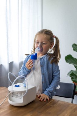Küçük bir kız öksürüğünde oksijen spreyi kullanarak evde nebulizatörle solunum yapıyor. Yüksek kalite fotoğraf