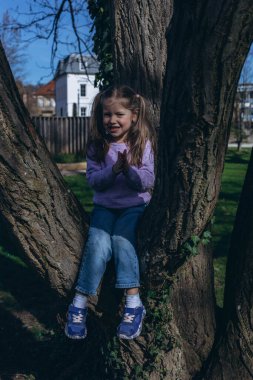  5 yaşındaki bir kız, parkta bisikletini sürüyor, gülümsüyor ve güneşli, yeşil ortamın tadını çıkarıyor. Yüksek kalite fotoğraf
