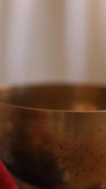 Şarkı söyleyen Tibet kâsesinde oynayan genç bir kadın. Rahatlama ve meditasyon. Şarkı söyleyen bir kâseye yakın çekim.