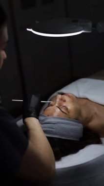 Orta yaşlı bir kadın kozmetik kliniğinde yaşlanma karşıtı yüz soyma tedavisi görüyor.