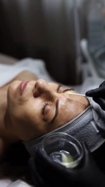 Orta yaşlı bir kadın kozmetik kliniğinde yaşlanma karşıtı yüz soyma tedavisi görüyor.