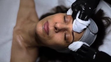 Orta yaşlı bir kadın kozmetoloji ofisinde yüz temizleme ve bakım görüyor. Yüksek kaliteli FullHD görüntüler
