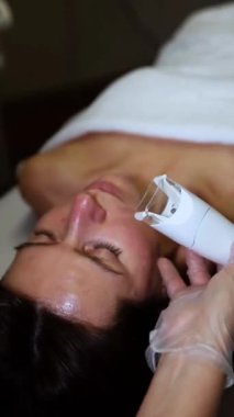 Profesyonel kozmetik uzmanı güzellik salonunda gençleştirme için LPG yüz masajı yapıyor..