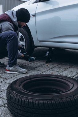 Adam arabasının lastiğini ingiliz anahtarıyla değiştiriyor, yerine kış lastiklerini takıyor. Yüksek kalite fotoğraf
