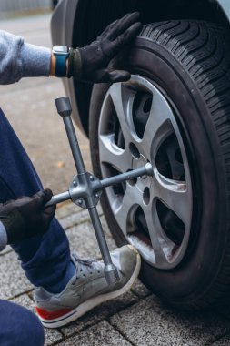 Adam arabasının lastiğini ingiliz anahtarıyla değiştiriyor, yerine kış lastiklerini takıyor. Yüksek kalite fotoğraf