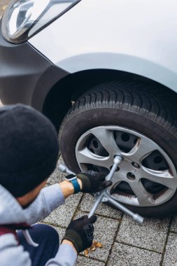 Adam arabasının lastiğini ingiliz anahtarıyla değiştiriyor, yerine kış lastiklerini takıyor. Yüksek kalite fotoğraf