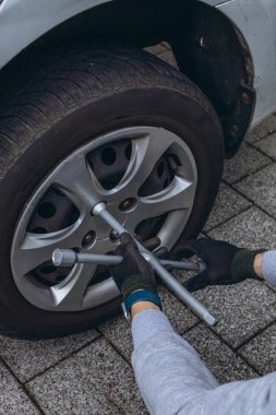 Delikanlı yolda lastik değiştiriyor, vidaları sökmek için İngiliz anahtarı kullanıyor. Yüksek kalite fotoğraf