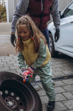 Küçük bir kız babasının arabasının lastiklerini değiştirmesine yardım eder. Yürekten bir bağ kurma deneyimi yaratır. Yüksek kalite fotoğraf