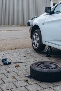 Adam arabasının lastiğini ingiliz anahtarıyla değiştiriyor, yerine kış lastiklerini takıyor. Yüksek kalite fotoğraf