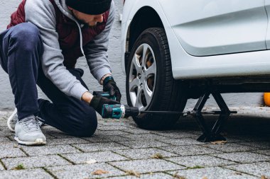 Adam arabasının lastiğini ingiliz anahtarıyla değiştiriyor, yerine kış lastiklerini takıyor. Yüksek kalite fotoğraf