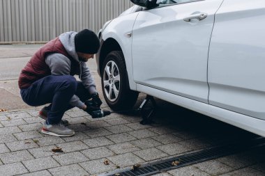 Delikanlı yolda lastik değiştiriyor, vidaları sökmek için İngiliz anahtarı kullanıyor. Yüksek kalite fotoğraf