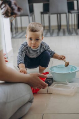 Anne ve bebek mutfakta tencere ve tavalarla oynuyorlar, oyalanıyorlar ve eğleniyorlar. Yüksek kalite fotoğraf