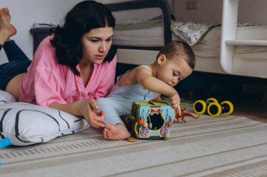 Anne ve bebek gelişimsel oyuncaklarla birlikte oynuyorlar, yerde oturup öğrenmeyi teşvik ediyorlar. Yüksek kalite fotoğraf