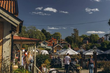 Stockholm, İsveç- 24 Ağustos 2024 Lakeside kafe, beyaz şemsiyeler, insanların dinlenmesi ve manzaralı su manzarasının tadını çıkarması. Yüksek kalite fotoğraf