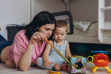 Anne ve bebek gelişimsel oyuncaklarla birlikte oynuyorlar, yerde oturup öğrenmeyi teşvik ediyorlar. Yüksek kalite fotoğraf