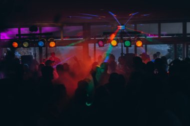 Stuttgart, Almanya-5 Nisan 2025. Elleri havada insanlar, diskoda, konser kalabalığının siluetleri parlak sahne ışıkları önünde. Yüksek kalite fotoğraf