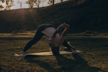 Doğada yoga yapan genç bir kadın. Kız dışarıda meditasyon yapıyor. İnce, güçlü ve esnek vücutlu bir kadın. Sağlıklı yaşam tarzları. Canlılık kavramı, sakinlik, rahatlama, farkındalık, zen enerjisi. Yüksek kalite fotoğraf