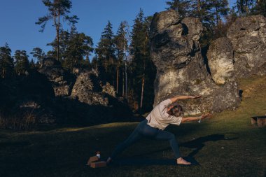 Doğada yoga yapan genç bir kadın. Kız dışarıda meditasyon yapıyor. İnce, güçlü ve esnek vücutlu bir kadın. Sağlıklı yaşam tarzları. Canlılık kavramı, sakinlik, rahatlama, farkındalık, zen enerjisi. Yüksek kalite fotoğraf