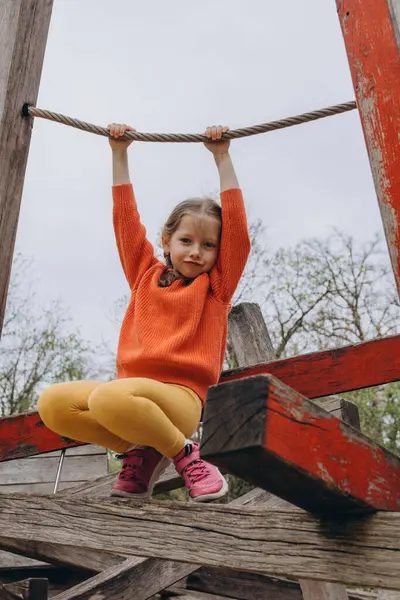 Tahta kirişlerden yapılmış bir oyun parkına tırmanan 5 yaşındaki bir kız yazın açık havada oyun ve maceranın tadını çıkarıyor. Yüksek kalite fotoğraf