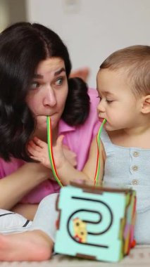 Anne ve bebek gelişimsel oyuncaklarla birlikte oynuyorlar, yerde oturup öğrenmeyi teşvik ediyorlar. Yüksek kalite 4k görüntü