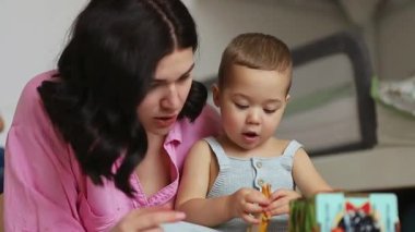 Anne ve bebek gelişimsel oyuncaklarla birlikte oynuyorlar, yerde oturup öğrenmeyi teşvik ediyorlar. Yüksek kalite 4k görüntü