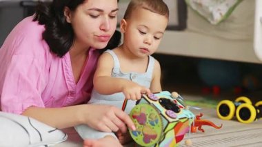Anne ve bebek gelişimsel oyuncaklarla birlikte oynuyorlar, yerde oturup öğrenmeyi teşvik ediyorlar. Yüksek kalite 4k görüntü