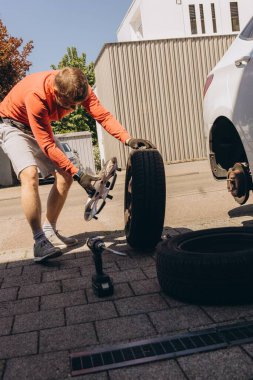 Adam araç gereçleri kullanarak yol kenarında lastik değiştiriyor, araç krikoda kaldırılıyor. Araba tamiri, bakım, arıza yardımı ve gerçek hayat durumları kavramı. Yüksek kalite fotoğraf