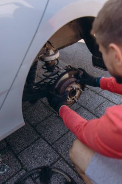 Adam araç gereçleri kullanarak yol kenarında lastik değiştiriyor, araç krikoda kaldırılıyor. Araba tamiri, bakım, arıza yardımı ve gerçek hayat durumları kavramı. Yüksek kalite fotoğraf