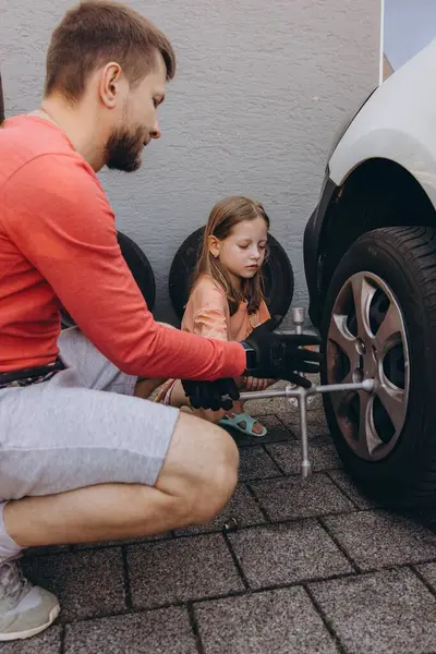 Küçük bir kız babasının arabasının lastiklerini değiştirmesine yardım eder. Yürekten bir bağ kurma deneyimi yaratır. Yüksek kalite fotoğraf