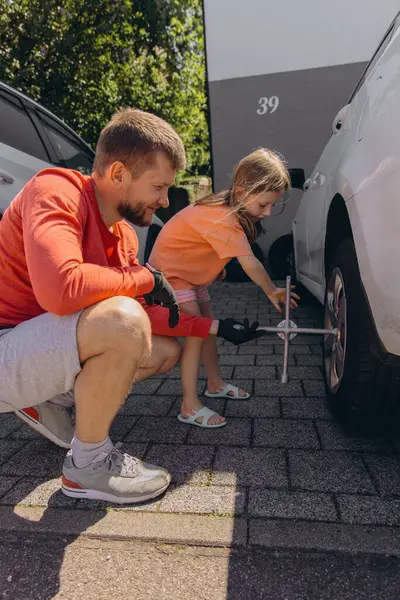 Küçük bir kız babasının arabasının lastiklerini değiştirmesine yardım eder. Yürekten bir bağ kurma deneyimi yaratır. Yüksek kalite fotoğraf